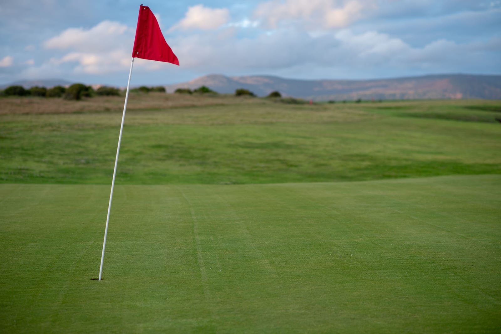 A red flag on a quiet green on a clear morning.